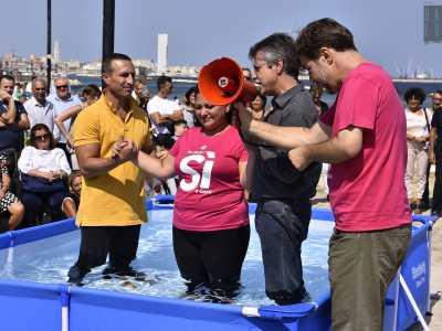 Uno per volta i fedeli entrano quindi nella piscina. Caito attraverso un megafono rosso chiede loro se sono convinti della loro scelta, se vogliono accogliere Cristo nella propria vita. E i battezzandi dopo aver affermato con forza la parole stampate sulla t-shirt...